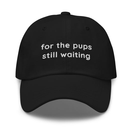 "For The Pups Still Waiting" trucker hat with embroidered text for dog moms, dog trainers, rescue volunteers, and pup people.